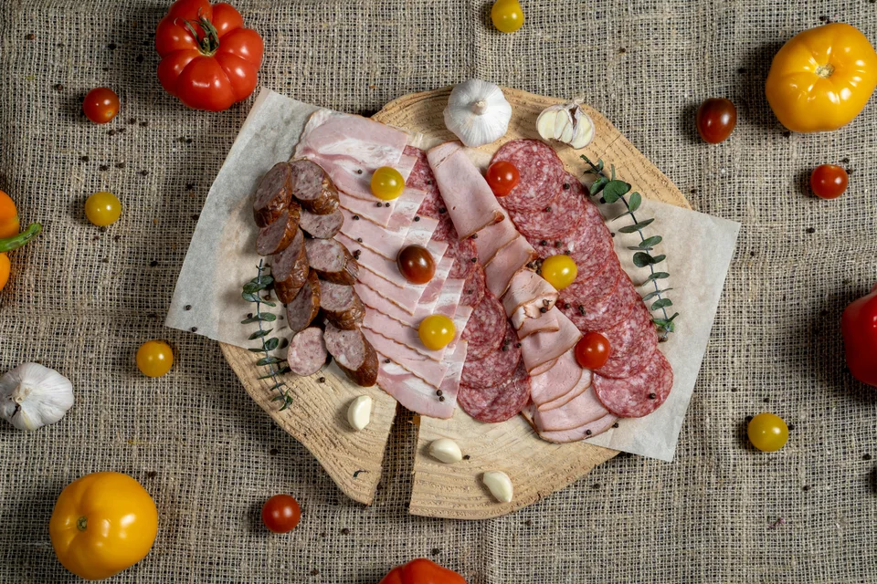 参考写真: 木のボードに盛り付けたスライスした加工肉とソーセージ